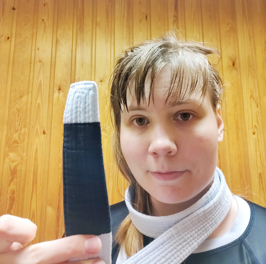 Human holding up a white belt with no stripes.