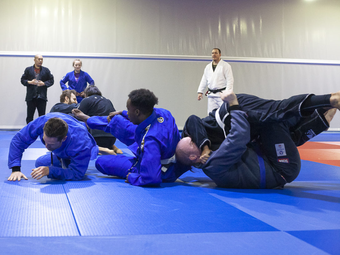 People rolling in a BJJ gym, two pairs of partners crashing in one another.